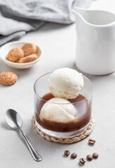 Affogato coffee with vanilla ice cream scoops and espresso in a glass on a light  background