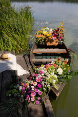 A serene boat adorned with vibrant flowers resting by a tranquil lake at midday, surrounded by lush greenery