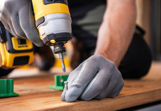 Man Using a Power Drill to Fasten Screws During a Home Improvement Project in the Afternoon