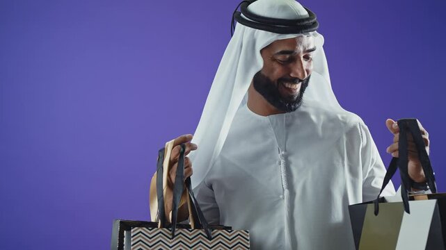 Handsome saudi arabian middle-eastern man with traditional thwab portrait in studio on colored backgrounds and gel colored lights.	
