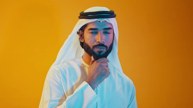 Handsome saudi arabian middle-eastern man with traditional thwab portrait in studio on colored backgrounds and gel colored lights.	
