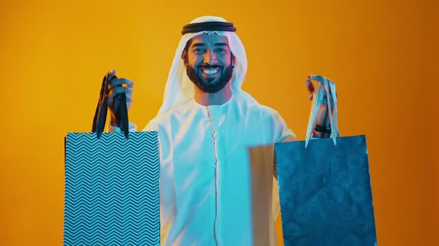 Handsome saudi arabian middle-eastern man with traditional thwab portrait in studio on colored backgrounds and gel colored lights.	
