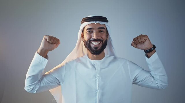 Handsome saudi arabian middle-eastern man with traditional thwab portrait in studio on colored backgrounds and gel colored lights.	
