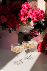 Elegant celebration with champagne and vibrant rose arrangements in a sunlit room adorned with floral beauty