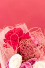 A vibrant bouquet of pink and red flowers beautifully arranged against a soft pink backdrop, creating a stunning display of nature's artistry