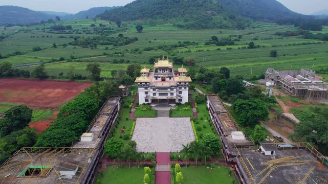 Aerial view of Jiranga Buddhist Monastery rests in a lush valley with hills around, featuring a golden-roofed main building and courtyards, creating a serene, peaceful atmosphere.
