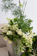 A vibrant arrangement of fresh white flowers and greenery in a modern vase graces a minimalist room setting in soft natural light