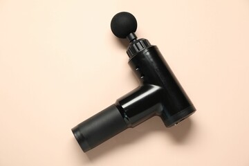 One black percussive massager on beige background, top view