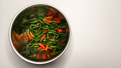 Top Left View of Stainless Steel Bowl Filled with Fresh, Colorful Red, Orange, and Green Chili Peppers on a Clean White Background – Spicy Ingredients for Cooking, Seasoning, and Culinary Inspiration