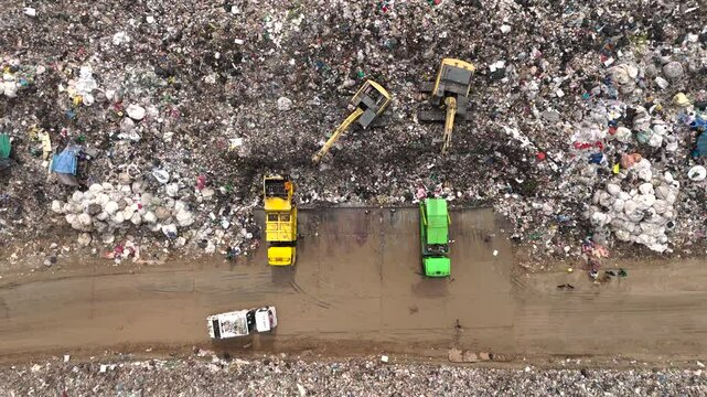 Aerial top view of A Huge Waste, garbage, dump, rubbish landfill. A landfill compactor, group of workers sort out the garbage in the landfill. Trash trucks dump waste polluting products.