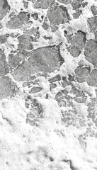 Close-up of foamy waves crashing on a rocky beach.