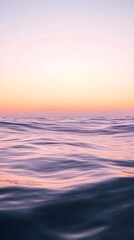 Fototapeta premium A calm sea at sunset, with the horizon blending into a gradient of purples and oranges, creates an atmosphere that feels serene and peaceful.