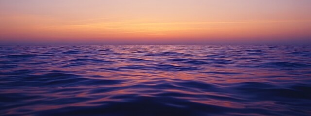Obraz premium A calm sea at sunset, with the horizon blending into a gradient of purples and oranges, creates an atmosphere that feels serene and peaceful.