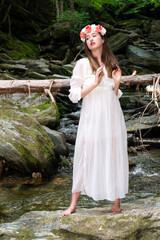 A woman in a white dress posing in a little water fall