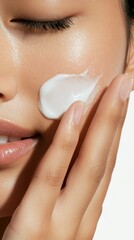 スキンケアのルーティン: 健康的な輝きのために保湿剤を塗る女性のクローズアップ