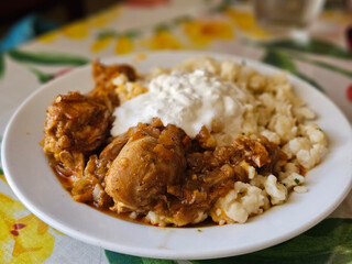 Hungarian chicken authentic Pörkölt serving with thin short noodle and white yogurt.