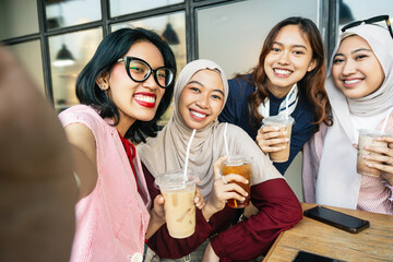 Asian girl friends friends sitting in cafe take a selfie with cell phone camera