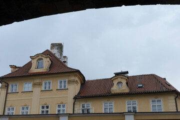 There exists a large yellow building that features a distinctive red tiled roof, creating a beautiful contrast against the sky