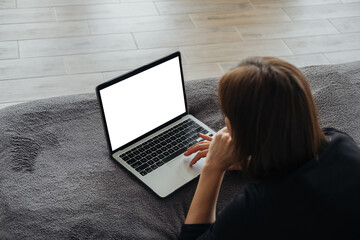 Woman working on a laptop while sitting on a cozy blanket at home
