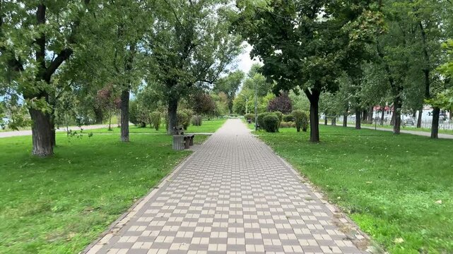 A park with a path and a bench. The path is made of bricks and the bench is made of wood