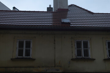 A quaint house featuring a charming chimney perched atop its roof, complemented by two inviting windows that adorn the facade