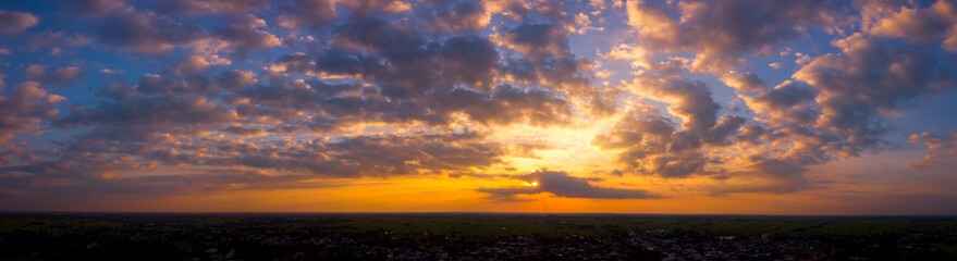 Fototapeta premium Panorama Top view Aerial photo from flying drone over rice fields in Thailand.Cumulus sunset clouds with sun setting down on dark background.