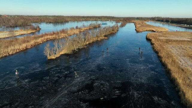 Ice skating on a frozen lake in the Weerribben Wieden nature reserve during a cold winter day in The Netherlands.
