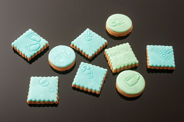 Baby cookies decorated with glaze on a black background. Baby boy.