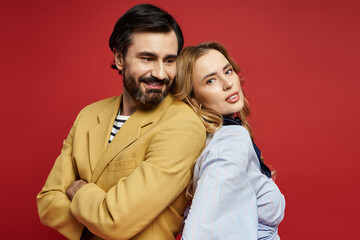 A cheerful middle aged couple shows off their lively personalities while posing back to back.