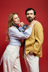 A middle aged couple stands confidently together, expressing their unique fashion styles.