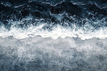 Waves crashing onto a sandy shore creating a mesmerizing pattern of white foam and dark blue water.