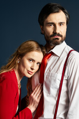 A middle aged couple dressed in stylish attire embraces intimately while posing together.