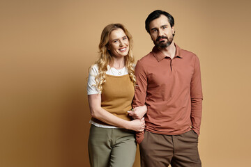 A middle aged couple stands close together, smiling happily in a charming studio setting.