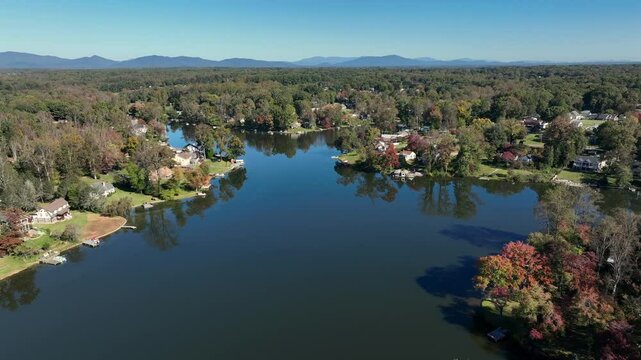 Timber Lake near Lynchburg during fall season. Idyllic landscape with villas at shoreline. Aerial rising wide shot. Virginia, United States of america. Sunny day with blue sky.