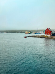 Upper deck views of the foggy harbor of Tórshavn, the Capital City of the Faroe Islands. Views of Scandinavian style architecture on the North Atlantic Ocean. The Faroe Islands Flag flies. 