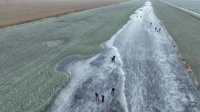 Ice skating on the Drontermeer floodplains near Elburg in nature seen from above during a cold winter day in The Netherlands.