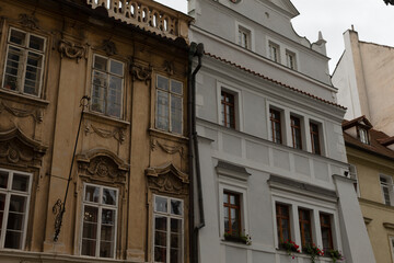 There is a white building featuring a balcony located right next to a brown building, creating a contrast in architectural styles