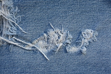 torn light grey denim surface, denim fringe , hole macro texture of blue denim, torn blue denim...