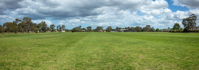 Panoramic background texture of a vast open grass field in Australia with houses and Eucalyptus...