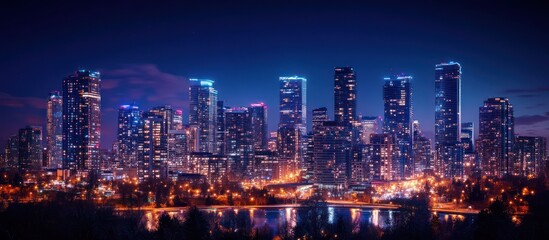 Fototapeta premium City skyline at night with tall buildings illuminated by lights reflecting in the water.