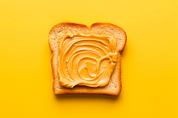 Toast with peanut butter on yellow background top view