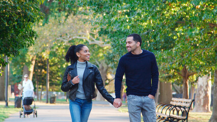 Obraz premium Loving Young Couple Outdoors Walking Through Park Holding Hands Together