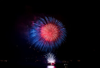 A vibrant red and blue firework bursts in the night sky, isolated against a black background.