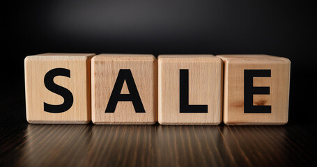 Wooden cubes with the inscription SALE on a dark background