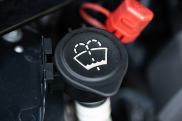 Car windshield washer fluid or screen wash icon on the black plastic container fill cap. Close up...