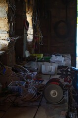 Interior of a workshop with various tools, cables, and equipment spread across a wooden workbench,...
