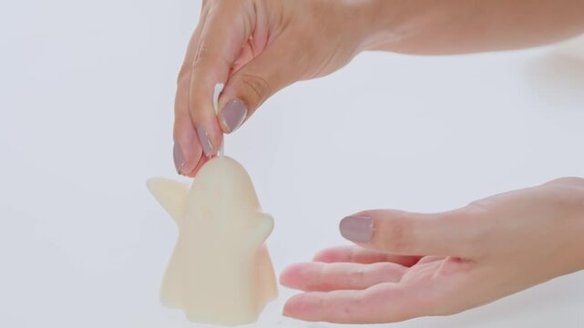 Close-up image of hands carefully holding a unique, handmade candle designed for relaxation and decoration. The wax features a distinctive shape, emphasizing creativity and craftsmanship.