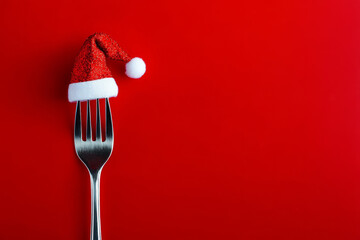 Christmas dinner. Cutlery fork wearing a red festive father christmas santa hat