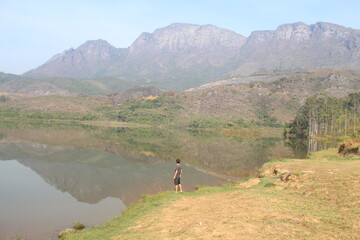 pessoa nas margens da represa do mosquito com serra do cara&ccedil;a ao fundo em catas altas, minas gerais 