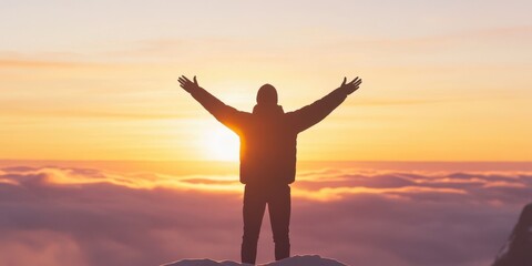 Person standing on a mountain with arms outstretched, sunset backdrop.